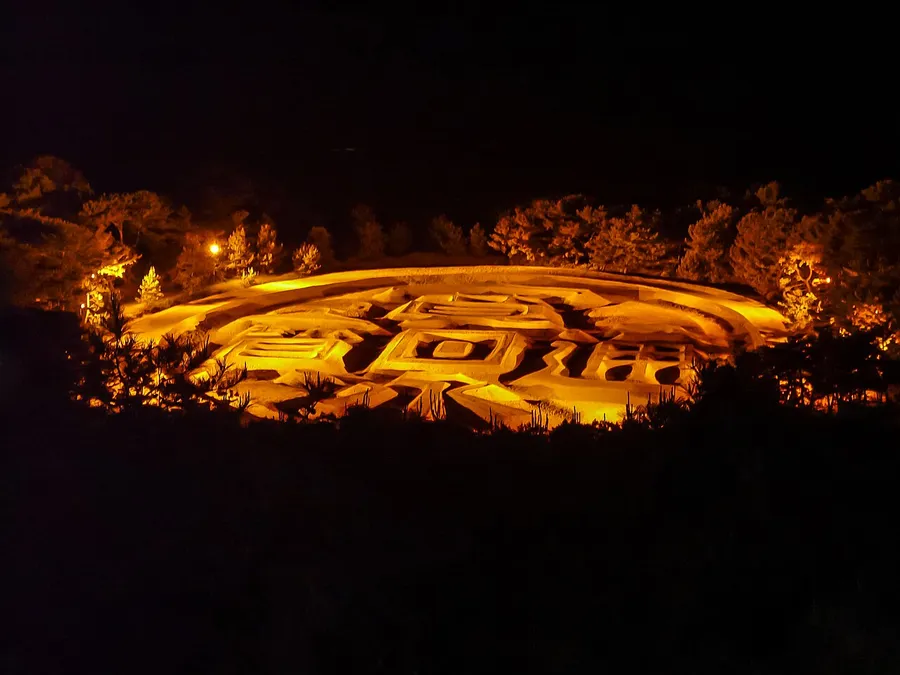 夜に黄金色の光で照らされた銭形砂絵